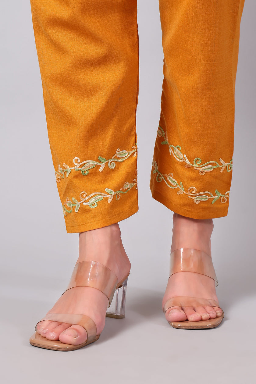 Detailed view of green Aari embroidery on amber co-ord set pants