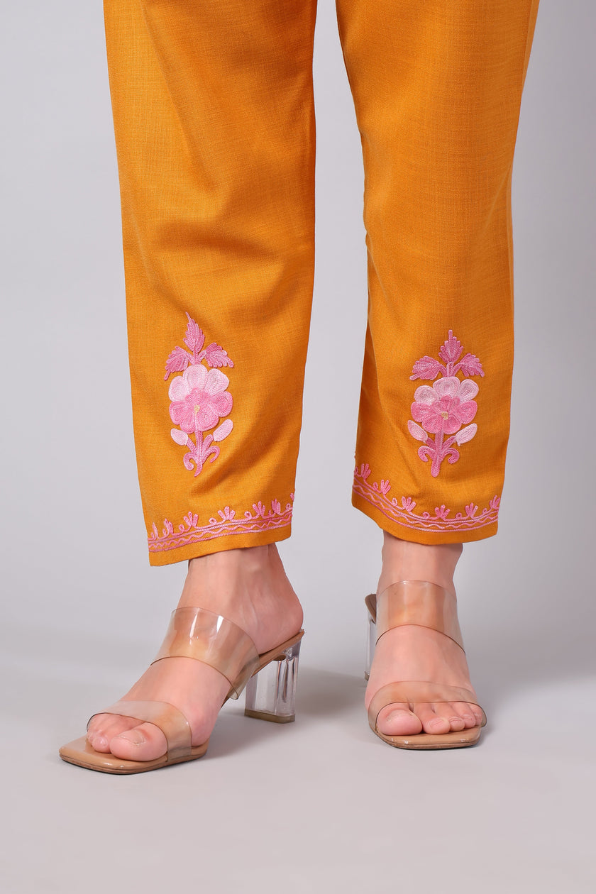 Detailed view of pink Aari embroidery on saffron co-ord set pants
